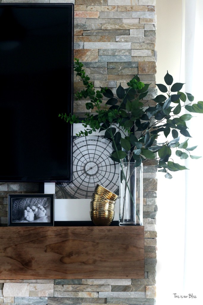 How to style a mantle - black white and gold display w pops of green on rustic floating mantle - stacked stone This is our Bliss www.thisisourbliss.com